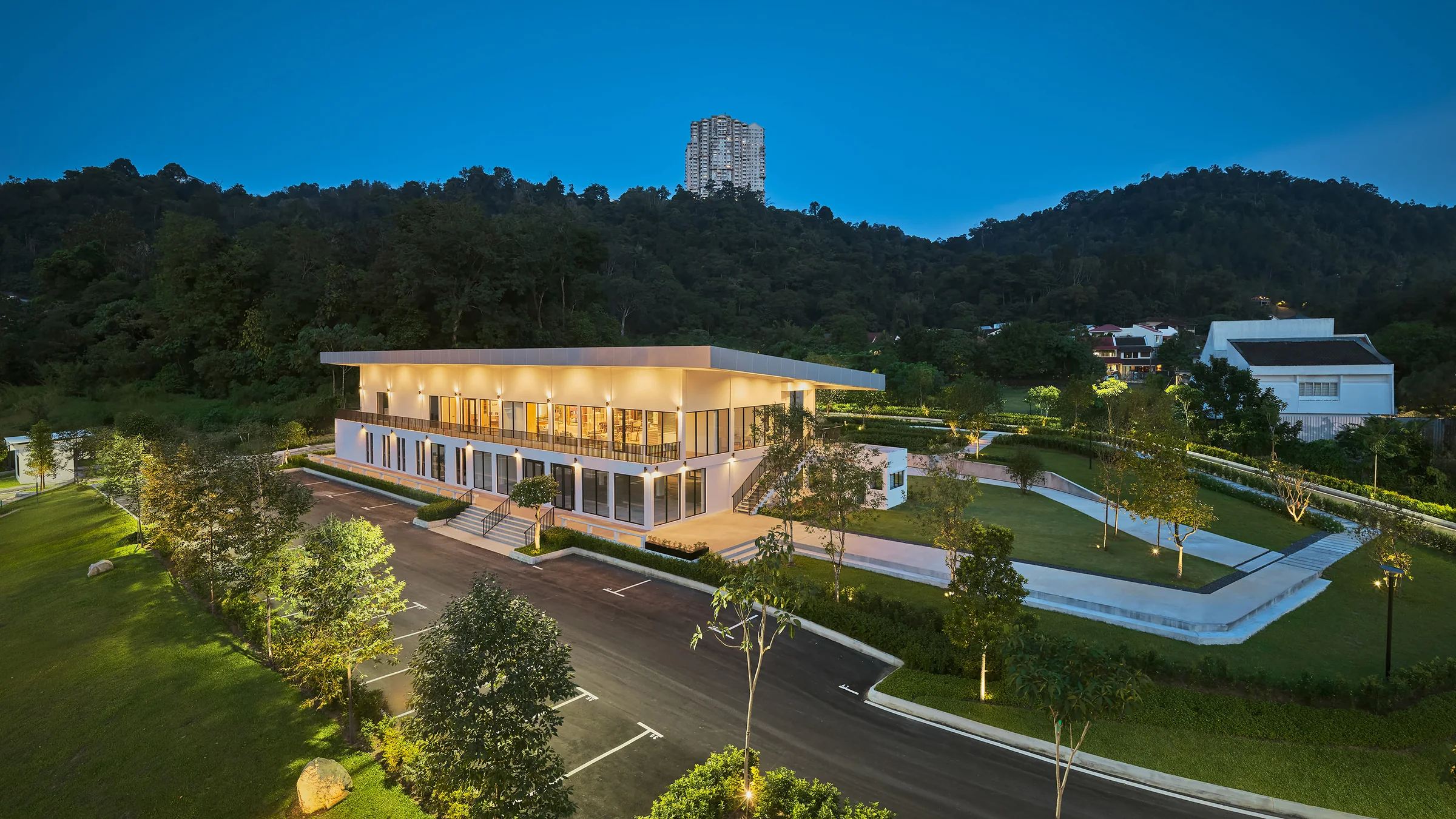 The sales gallery at night, the hillside dark behind it